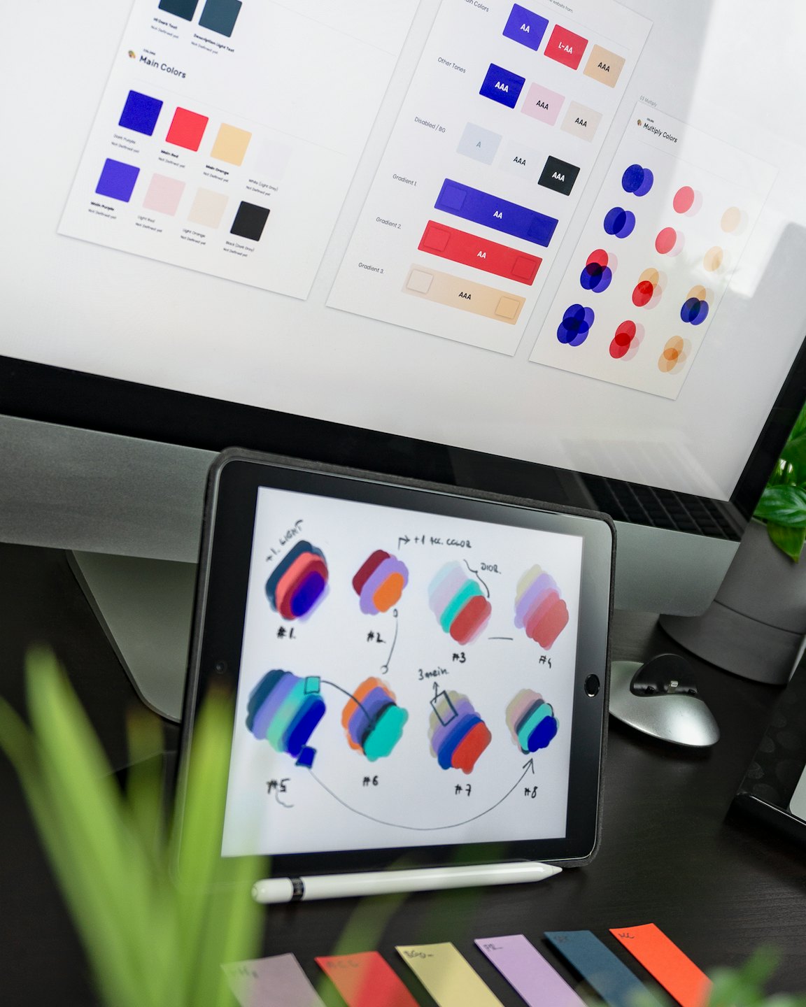 Monitor komputer dan tablet menampilkan pekerjaan desain dan sampel warna.